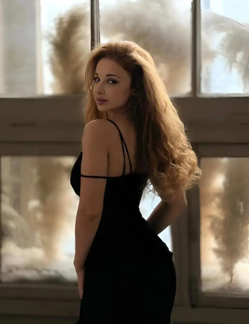 Woman with long wavy hair in a black dress.