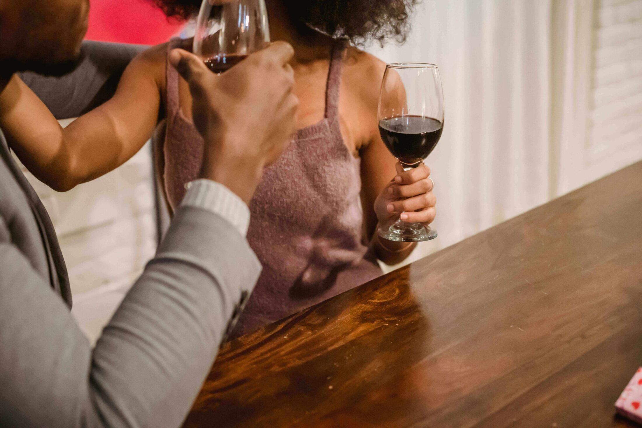 A couple toasts with glasses of red wine.