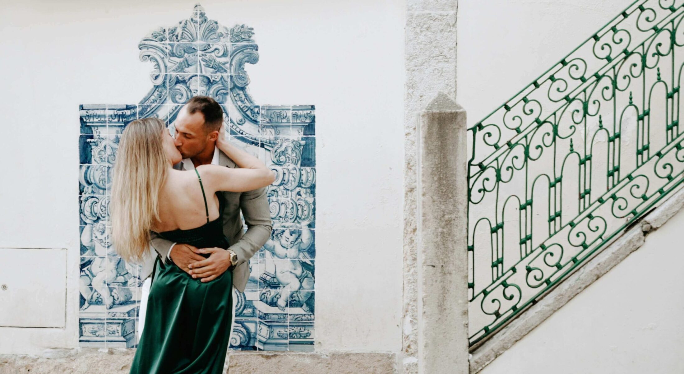 Couple kissing in front of blue decorative wall tiles.