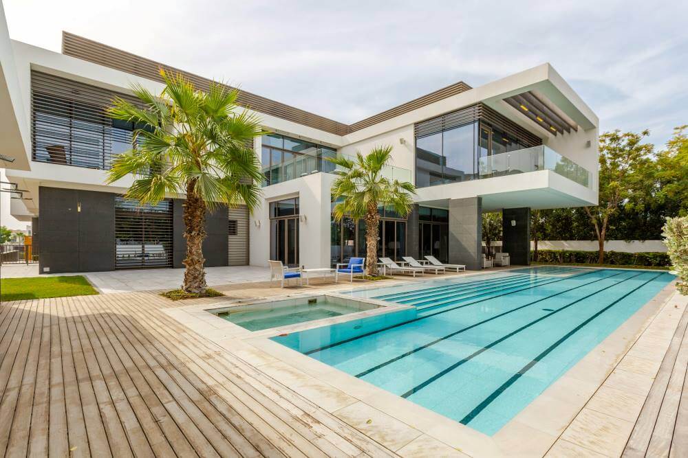 Modern luxury villa with a large swimming pool and palm trees.