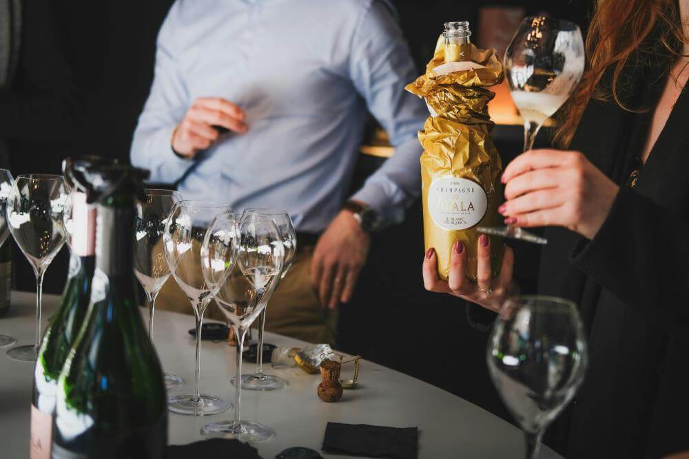 Ayala champagne bottle in gold foil at a social gathering.